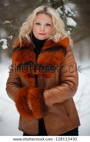 Pretty young Woman in snow winter forest dressed in fur coat