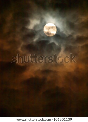 Spooky Moon. Reflections of a full moon producing orange brownish shadows on the surrounding clouds.