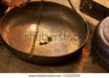 Weighing a gold nugget on a old brass scale dish for trade or exchange.