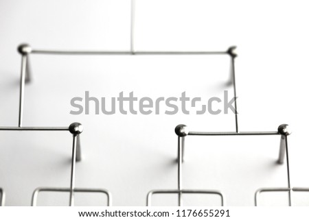 Hierarchy, command chain, company / organization structure or layer concept image. Top down structure made from chrome wires and chrome nails on white. Shallow depth of field.