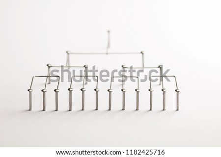 Hierarchy, command chain, company / organization structure or layer concept image. Top down structure made from chrome wires and chrome nails on white. Shallow depth of field. incandescent type light.