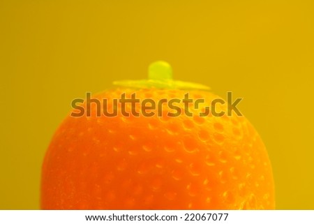 Macro shot of a toy orange, shot on yellow background with soft focus and lighting.