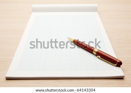 Blank graphing paper pad and pen isolated on white.