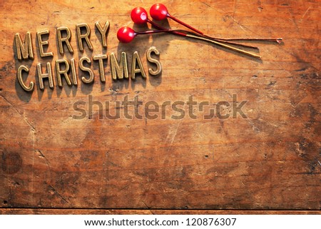 MERRY CHRISTMAS in brass lettering on a very old and worn wooden surface, Incandescent lighting.