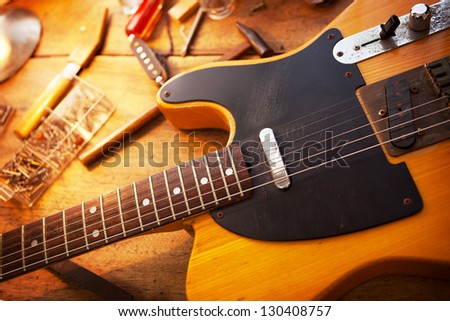 Guitar on guitar repair desk. Vintage electric guitar on a guitar repair work shop. Single cutaway electric guitar, amber color.