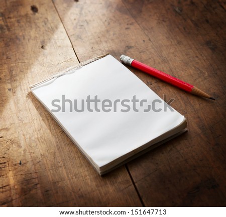 Memo pad on a well used old wooden surface with pencil.