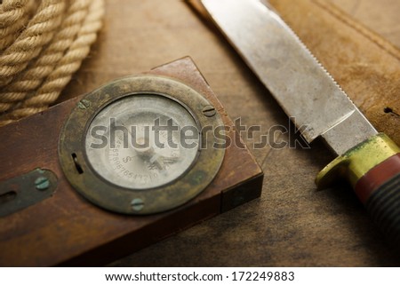 Old knife, compass, and rope on a old wooden desk, Exploration, survival, and hunting concept image.