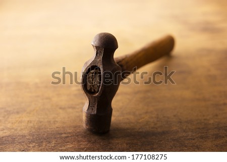 Hand forged hammer, hitting face down on a old wooden table.