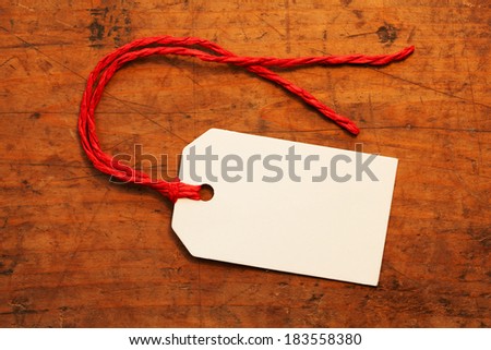 A blank paper tag with red string, on a old wooden desk
