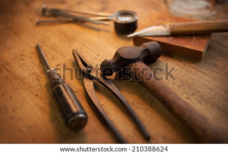 Old workshop. Old and well used hammer, pliers and screw driver with warm lighting.