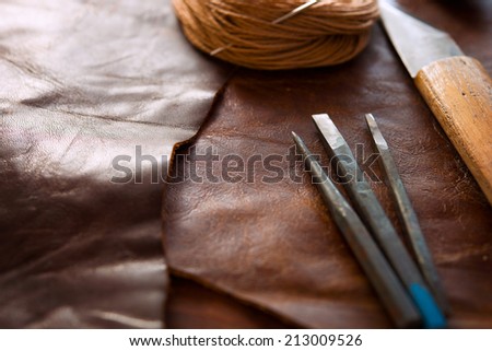 Leather craft.  Leather and leather crafting tools on a work table.