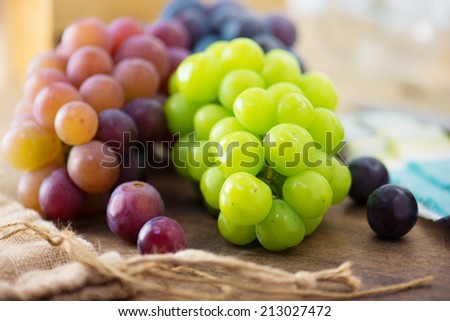 Harvest season. Fresh harvested red, black and white (green) grapes on a table, with table setting in background.