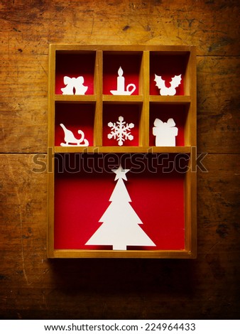 Christmas decoration, hand cut paper craft in a wooden printer tray, on a old wooden wall. .