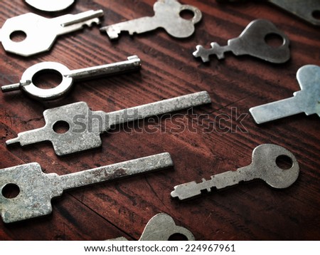 Distinctive keys. Many odd shaped keys on old wood table . Security and encryption, concept image.