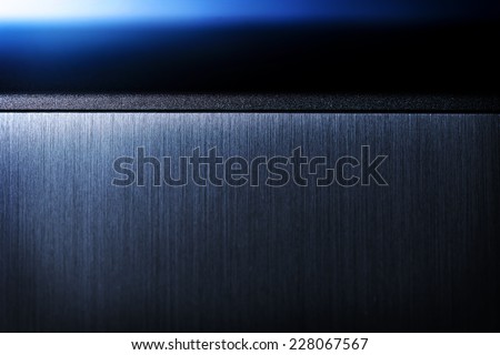 Sharp edged brushed metal and blue light background.?Shallow depth of field.