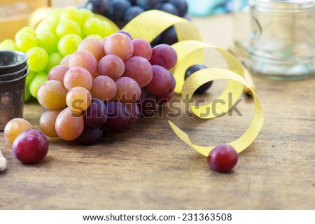 Party table with grapes. Fresh harvested red, black and white (green) grapes on a table, with table setting in background.