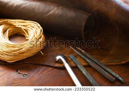 Leather craft. Leather and leather threading or sewing tools on a work table.
