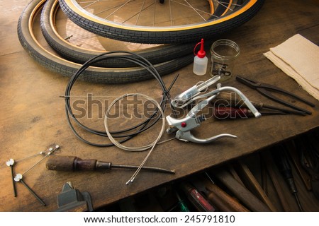 Bicycle repair. Repairing or changing a tire, brakes etc of an vintage bicycle. Old bicycle wheels on a grungy work desk with well used tools and bicycle parts.