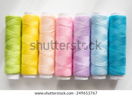 Spring colors. Light colored sewing threads on a white table with warm spring sunlight by the window .