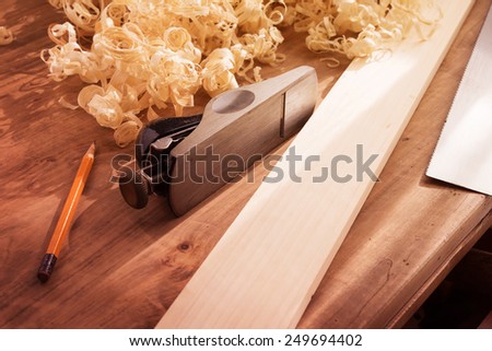 Wood working desk near the window with incandescent lighting, Wood working tools and wood shavings. Intentionally shot with low key shadows and shallow depth of field.