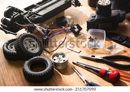Building model cars. Radio control car assembly scene, RC car assembly on wooden work desk and tools. Natural lighting.