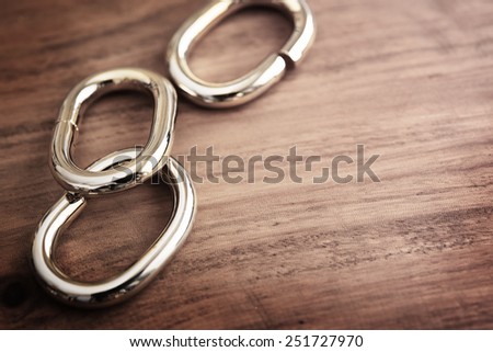 Chain links or chrome metal links on a grungy wooden table. shallow depth of field.