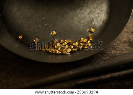 Found gold. gold panning or digging. Gold on wash pan. Intentionally shot with low key shadows and shallow depth of field.