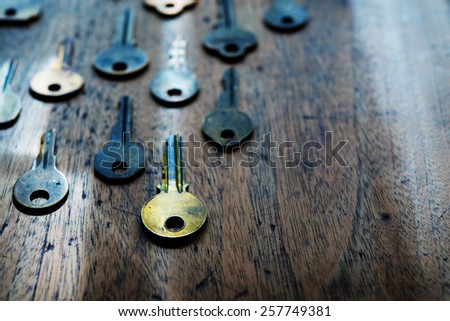 Grungy brass keys aligned in on a old wooden desk. Security and encryption concept image. Shallow depth of field. Focus is on forehand gold key. Intentionally shot in surreal color.