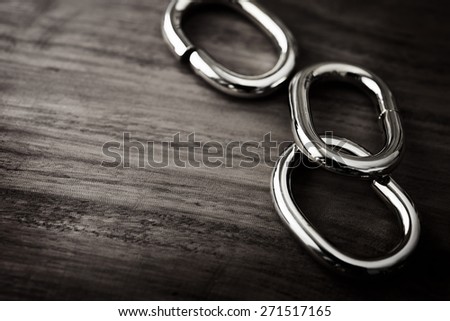 Shiny Chrome or silver chain links on a grungy wooden table. shallow depth of field.