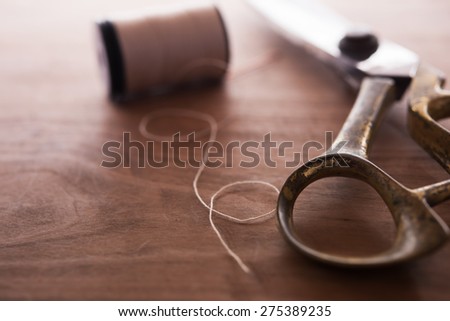 A gold scissors and spool of thread, Intentionally shot in nostalgic tone. Extremely shallow focus.