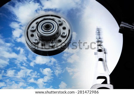 Cloud storage or cloud drive concept image. Hard disk (HDD or Hard drive) with clouds and sky reflecting on disk. Head and Axis with motion blur.