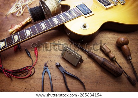 Guitar on guitar repair desk. Vintage electric guitar on a guitar repair work shop. Single cutaway solid body guitar, gold color.