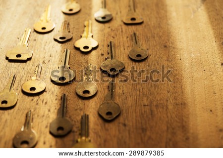 Various vintage brass keys aligned in the same direction on a old wooden desk. Security and encryption, concept image. Shallow depth of field.