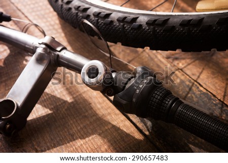 Bicycle repair. Bicycle handle bar and wheel on a wooden work bench. Intentionally shot with low key shadows. Shallow depth of field. Focus is on Shift selector of the handle bar.