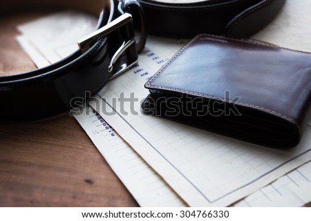 Documents, belt and a wallet on a wooden desk. hotel table or gentleman\'s desk. shallow depth of field.