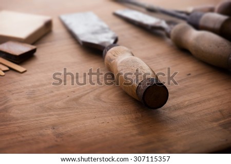 Old and well used wood working chisels, on a old workbench. Old chisel with an oak handle. Shallow depth of field.