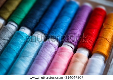Colored sewing threads. Focus on purple thread. Shallow depth of field.