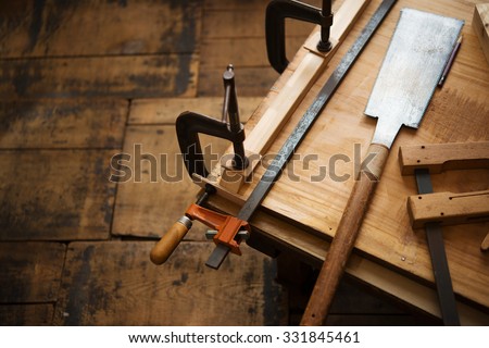 Woodworking. Wood working project on work bench, in a workshop with wooden floor. Clamped pieces of wood with c-clamps and bar clamp. shot in low key and shallow depth of field.