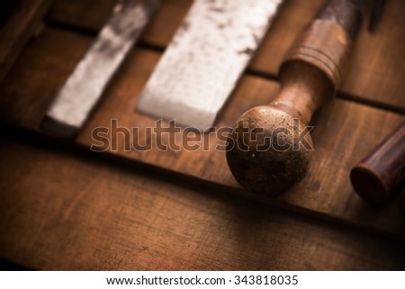 Old and well used wood carving chisels, prepared on a old workbench. Old chisel with an oak handle. Shallow depth of field. Low key.
