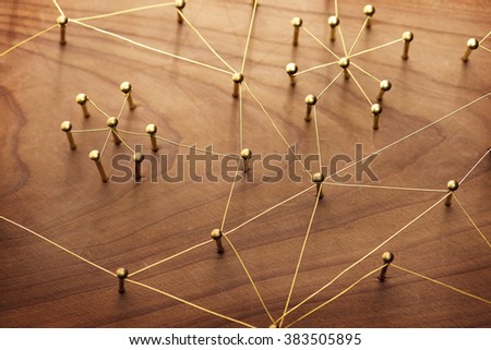 Linking entities. Network, networking, social media, internet communication abstract. A small network connected to a larger network. Web of gold wires on rustic wood.