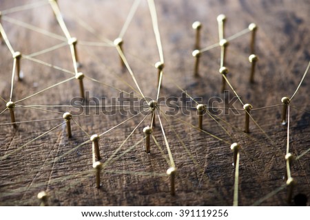 Linking entities. Network, networking, social media, internet communication abstract. A small network connected to a larger network. Web of gold wires on rustic wood.  Network hub or key person.