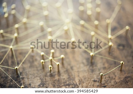 Linking entities, blurred background, or off-focus background. Network, networking, social media, internet communication abstract. Web of gold wires on rustic wood.