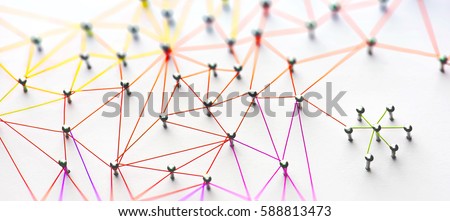 Linking entities. Networking, social media, SNS, internet communication abstract. Small network connected to a larger network. Web of red, orange and yellow wires on white background. Shallow DOF.