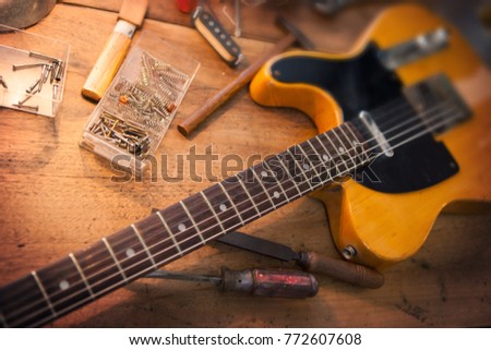 Guitar repair workbench. Vintage electric guitar on a guitar repair work shop. Single cutaway electric guitar, amber color.