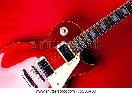 Deep red metallic vintage solid body electric guitar on deep red background.