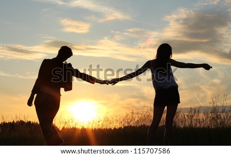 teenage sisters holding hands, silhouettes at sunset