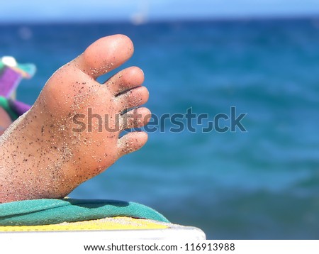 closeup of a female sole of foot, relaxing on beach, blue water background
