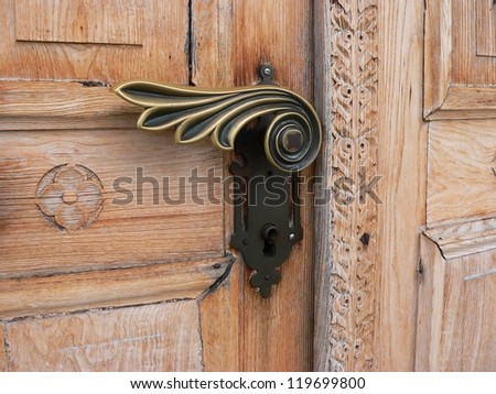 closeup of an antique door with ornate handle and carved wood pattern