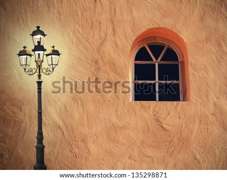structured mediterranean facade with arched window and burning street light