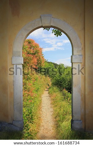 walkway through arched old door, mediterranean springtime landscape
